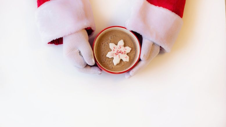 person wearing white gloves holding cup of hot cocoa